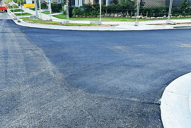 Freshly paved asphalt road with smooth surface and curved edge.