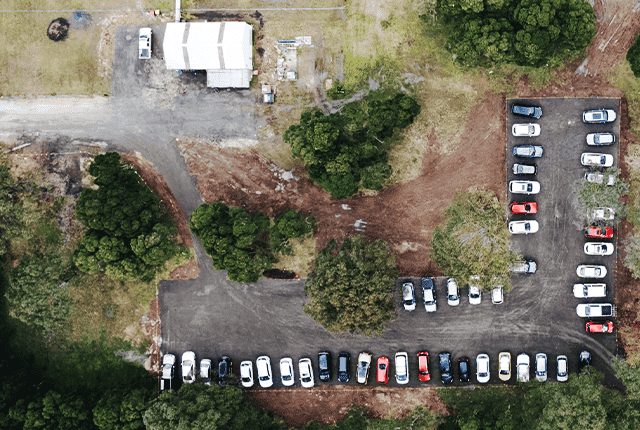 Aerial view of a car park with parked vehicles and surrounding greenery.