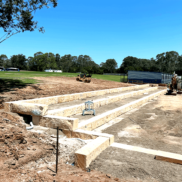 Construction site with stone retaining walls and heavy machinery.