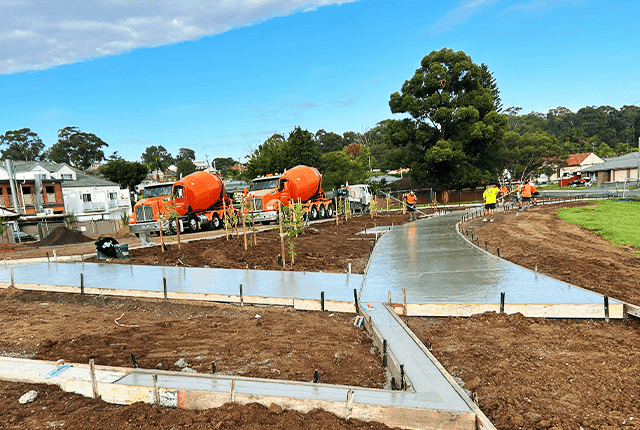 Concrete pathway being poured and smoothed at a construction site.
