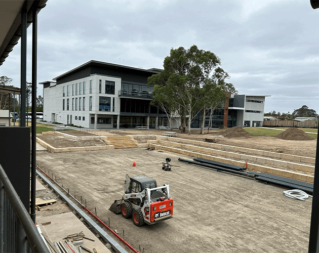 Construction site with a modern building in progress and heavy machinery present.