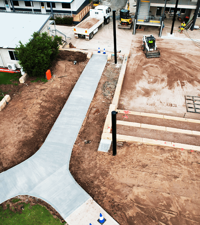 New concrete pathway and landscaping under construction at a commercial site.