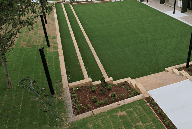 Beautiful landscaped yard with artificial turf and garden beds.