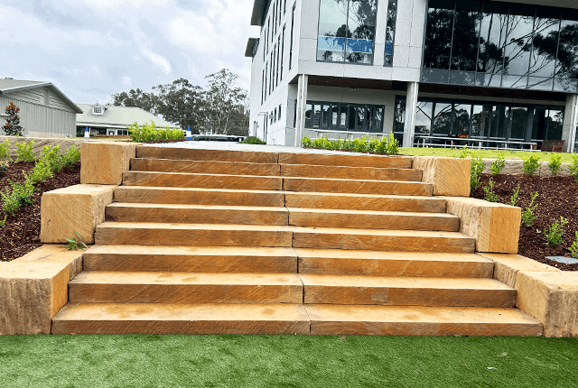Stone retaining wall with steps in front of modern building.
