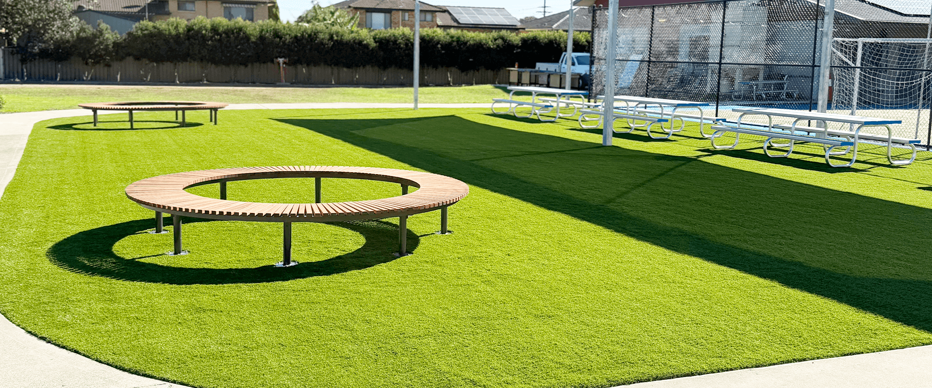 Colorful circular benches on a vibrant green artificial turf at a sports facility.