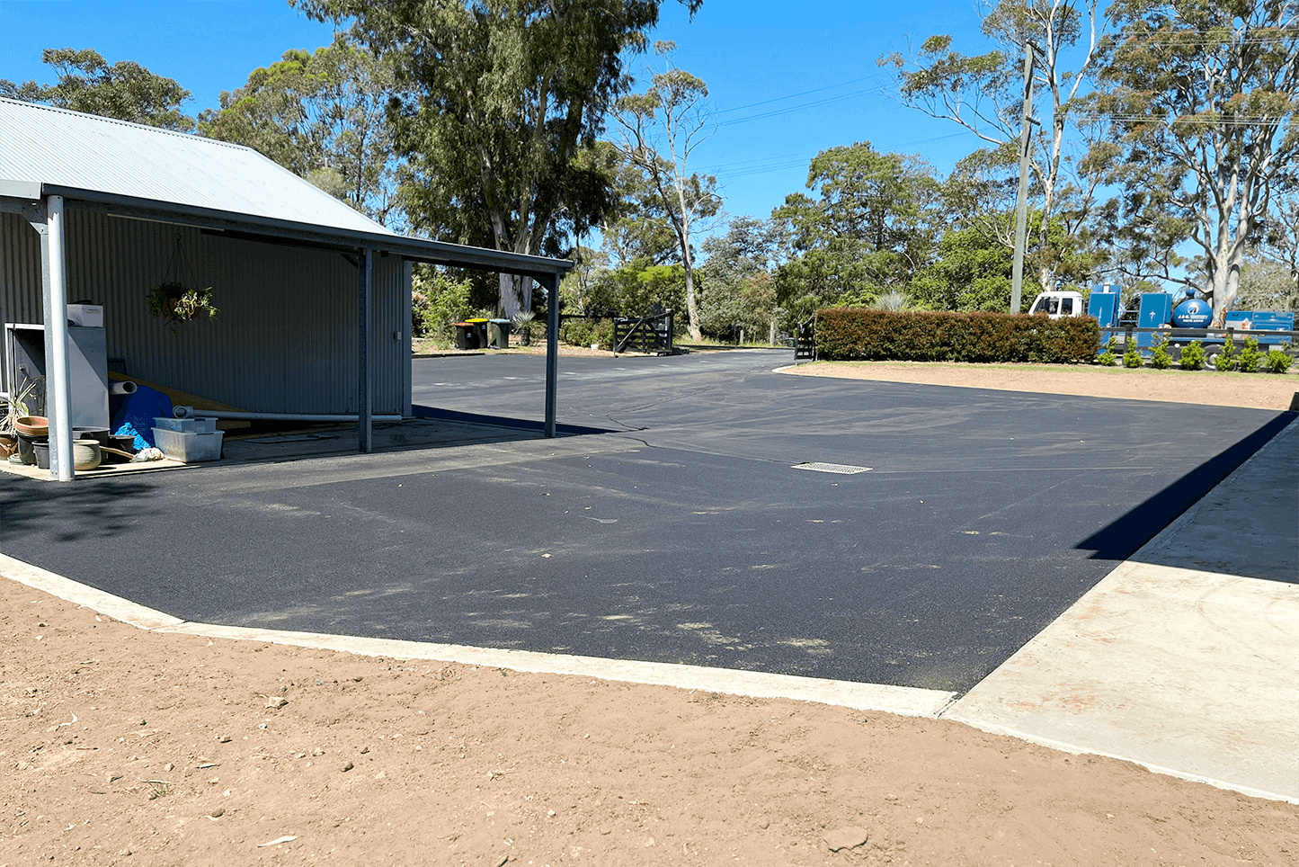Newly paved asphalt driveway in Glenorie with surrounding trees and clear sky.