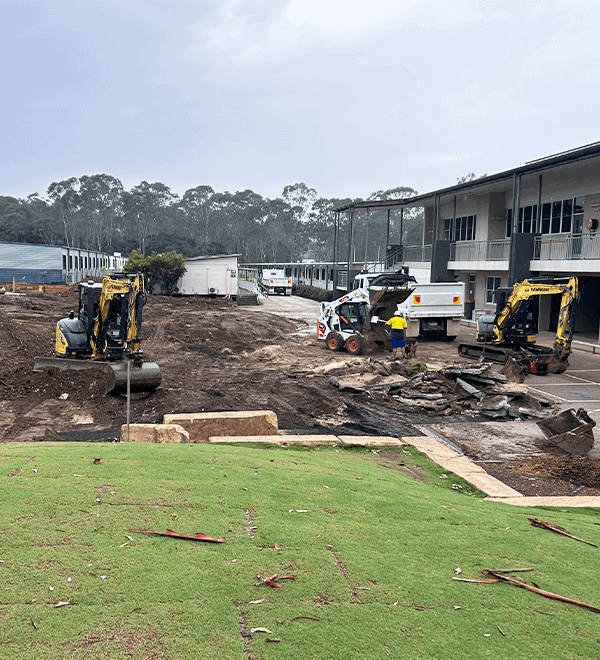 Construction site with excavators and workers near residential buildings.