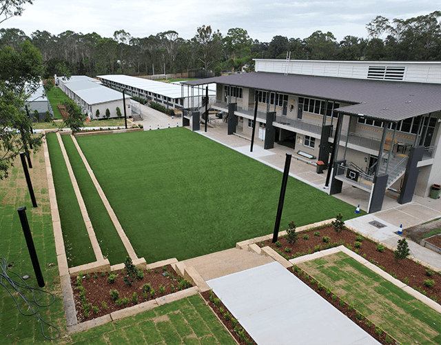 Modern commercial building with landscaped green space and outdoor seating area.