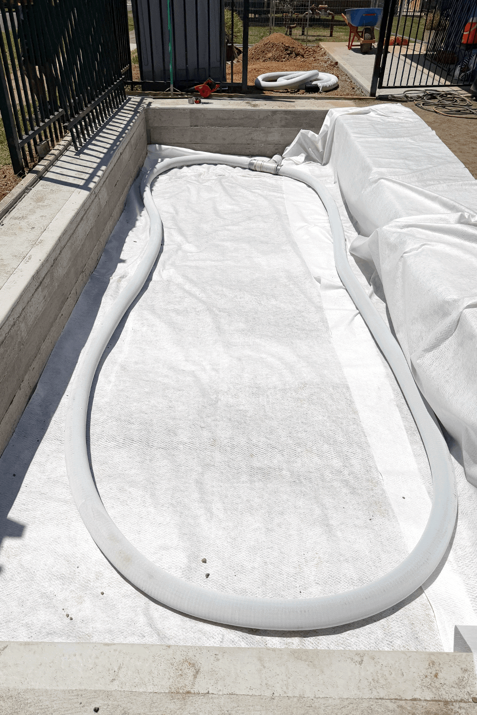 Construction site with pool liner and piping for pool installation.