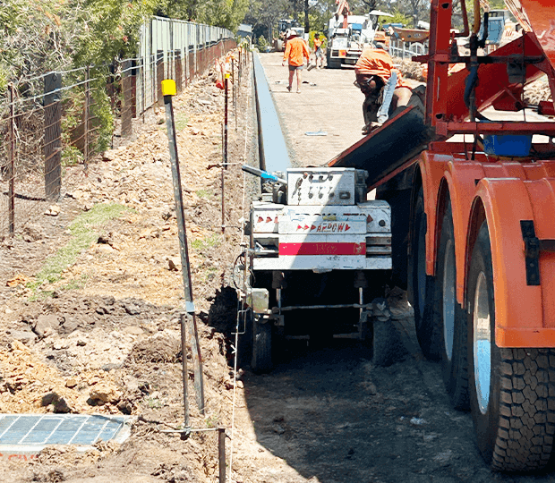 Construction workers and machinery working on road infrastructure project.