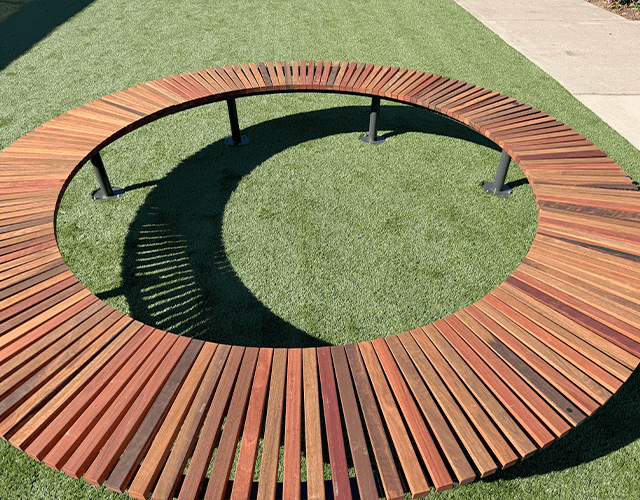Contemporary wooden circular bench in a park setting for sustainable outdoor spaces.